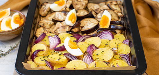 Recept van het Voedingscentrum: Traybake met aardappelpartjes, aubergine en rode ui